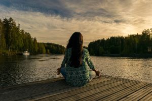Symbolbild einer Frau am See, welche meditiert